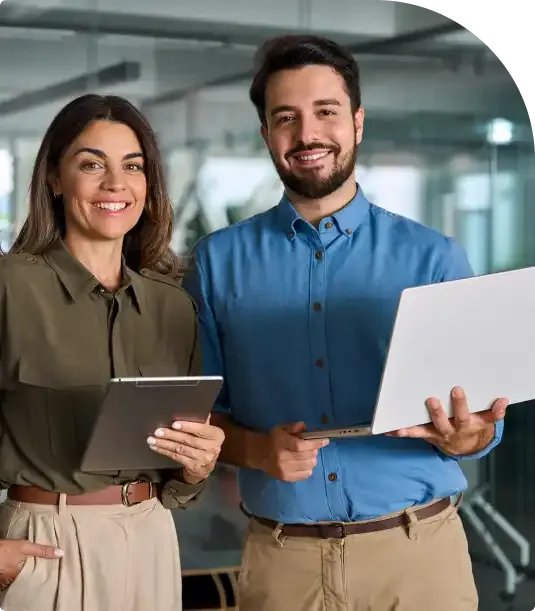 Dos profesionales sonrientes con una tableta y un portátil en una oficina acristalada