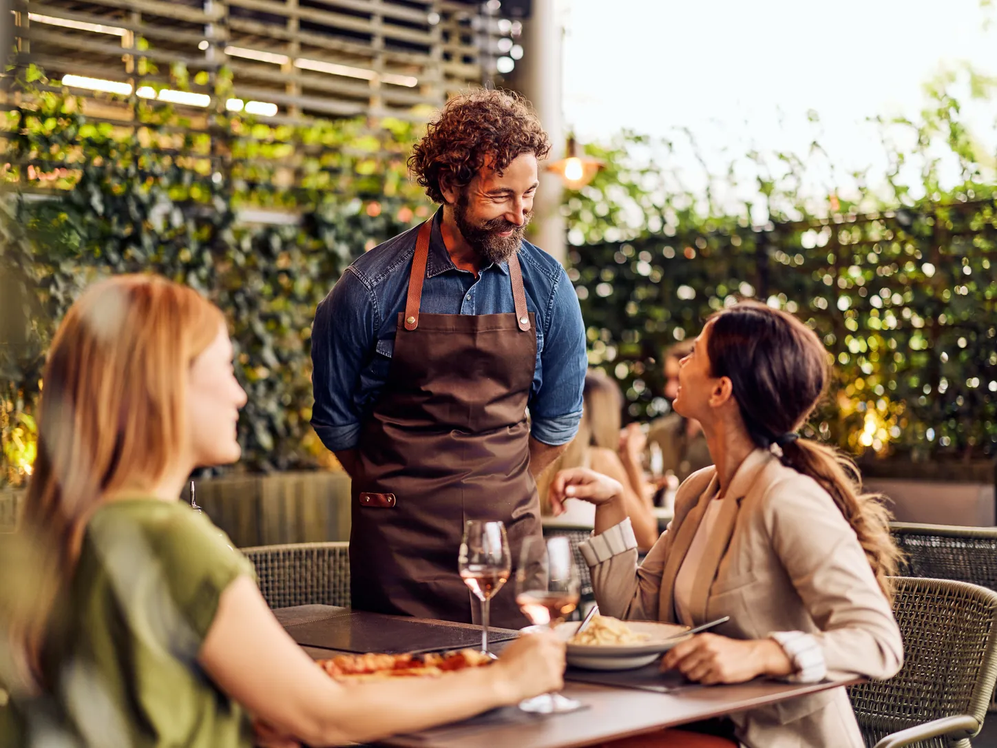Camarero atiende a dos clientas en la terraza de un restaurante